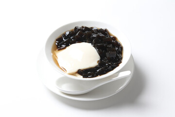black herbal grass jelly with white soya milk pudding and sweet syrup sauce in white bowl yuan yang asian traditional dessert halal vegan food menu for Hong Kong cafe