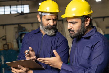 Professional worker or labor discussing some topic and writing detail at factory