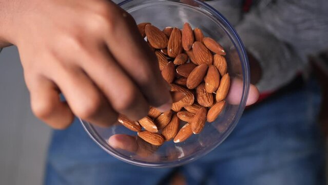 top view of hand pick almond nuts from a bowl 