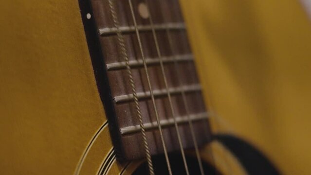 Plucking various strings on an old guitar in slow motion.