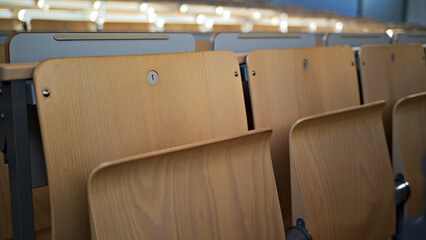 Klappsitze die typisch für eine Universität oder andere Bildungseinrichtungen sind. Der Fokus liegt auf Sitz mit der Nummer "1".