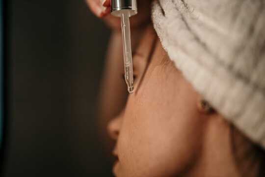 A woman is using anti aging serum treatment on her face in the bathroom