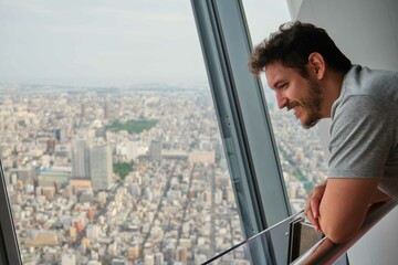 Fototapeta na wymiar Latin tourist man enjoying the views at the Tokyo Skytree, Japan.