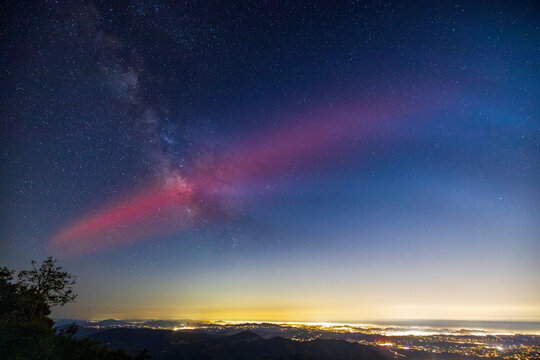 Milky Way galaxy core and red glow from SpaceX rocket launch. Lights of San Diego County below.