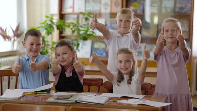 Children do a school project together. Having fun and looking at books sitting at desks. Team work on the task. Back to school.