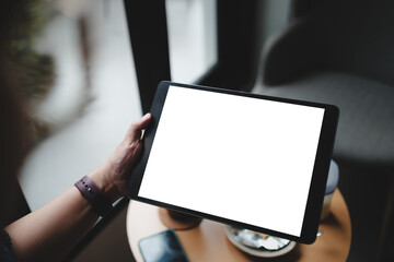 Woman's hand showing digital tablet blank screen on work desk.