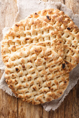 Greek freshly baked flat pita bread close-up on a wooden table. Vertical top view from above