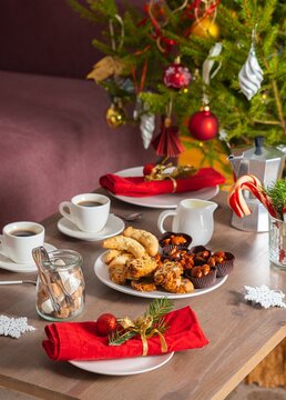 A Christmas-style coffee table with Christmas cookies beside a dark pink sofa. Christmas concept, table setting