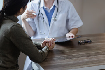 female doctor with female patient and telling advices sitting at workplace in clinic office,...