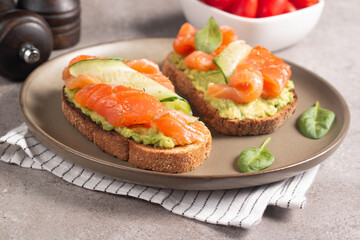 Two tasty open salmon sandwiches with avocado and cucumber. Morning healthy breakfast. Top view.