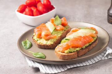 Two tasty open salmon sandwiches with avocado and cucumber. Morning healthy breakfast. Top view.