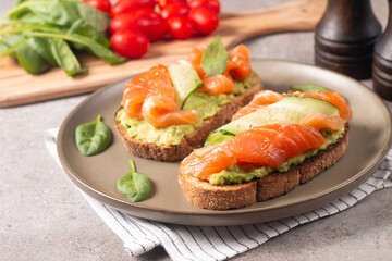 Two tasty open salmon sandwiches with avocado and cucumber. Morning healthy breakfast. Top view.