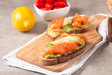 Two tasty open salmon sandwiches with avocado and cucumber. Morning healthy breakfast. Top view.