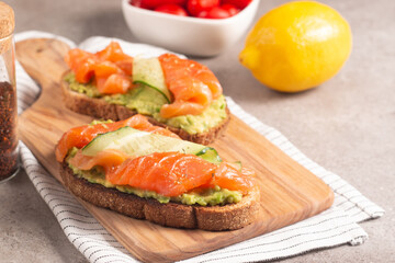 Two tasty open salmon sandwiches with avocado and cucumber. Morning healthy breakfast. Top view.