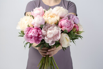 Woman hands holds a bouquet of many colored peonies isolated on white background