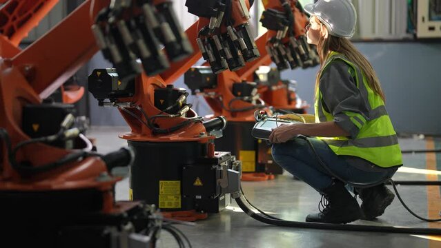 Technology and industrial processes, industrial engineer working on automated robotic arm in factory.