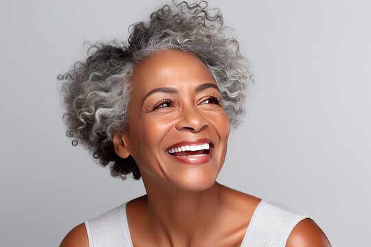 Happy laughing African American 50 years old woman. Happy woman on a grey background. The concept of health care, mental health.