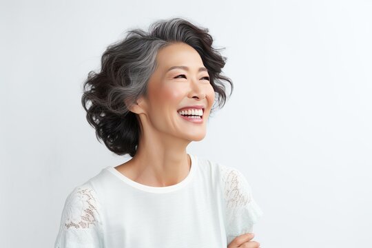 Happy laughing Asian 50 years old woman. Happy woman on a grey background. The concept of health care, mental health.