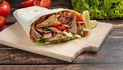 Turkish doner kebab, shawarma, roll with meat and pita bread on a wooden background, selective focus