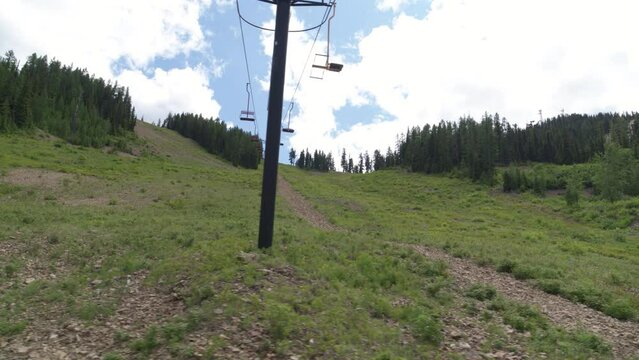 Aerial panning underneath chair lift in summer looking up at grassy ski slope in northern Idaho