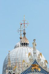 Fototapeta na wymiar Cover page with decoration elements at facade roofs and cupolas of Basilica San Marco in Venice, Italy, at blue sky and copy space