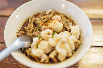 Thai Boat noodle thicken soup with Pork, balls, crispy fried pork skin, basil leaf and Vegetables. Traditional and Famous Street food in Thailand