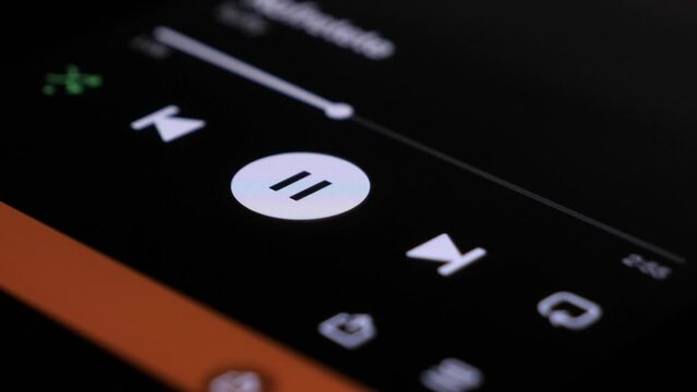 Tapping Pause Icon On Touchscreen On Spotify And Skipping Track Whilst Video Plays On Screen In Background. Close Up Shot