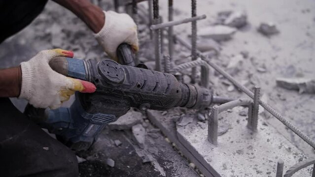 construction worker crumbles concrete with a jackhammer