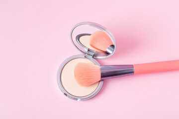 Beautiful eyeshadow palette with makeup brush lie on the pink background top view. Makeup product