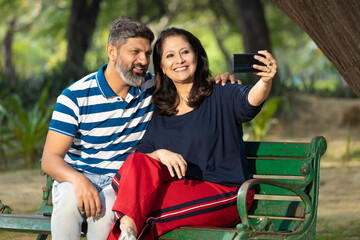 Indian couple taking selfie in smartphone at park