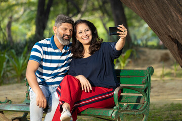 Indian couple taking selfie in smartphone at park