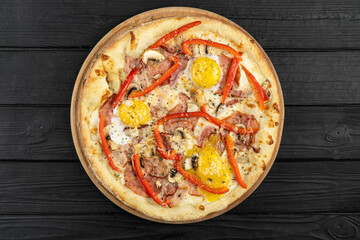 Top view of pizza with bacon, egg and red pepper
