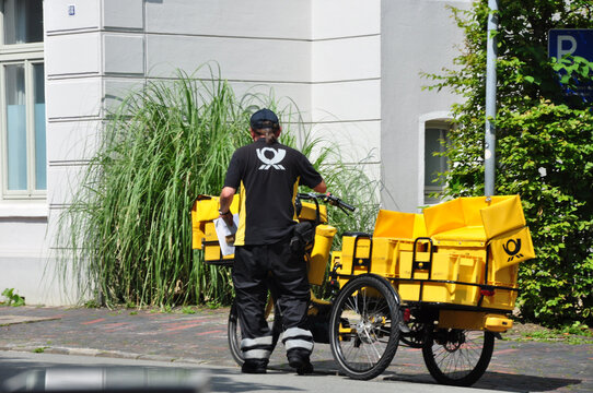 Deutsche Post: Der Auslieferungsfahrer von Postsendungen unterwegs mit dem Fahrrad. 