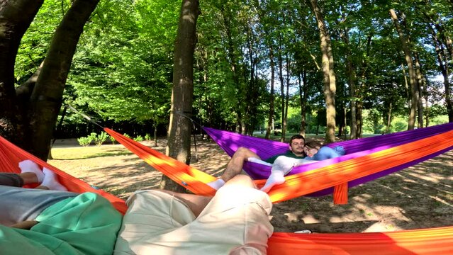 happy friends on hammocks in public park