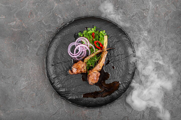 grilled meat with smoke on a black plate
