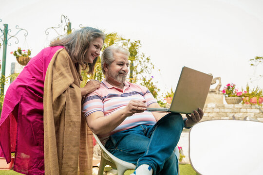 Senior Indian Couple using laptop at home garden