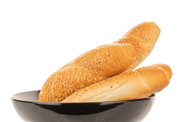 Four fragrant bagels sprinkled with sesame seeds in a black ceramic plate, close-up, isolated on white.