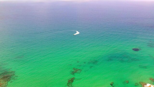 A slow-motion aerial view of a boat floating in the sea in the city of Hersonissos on the Greek island of Crete.