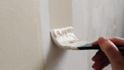 Slow application of light color paint on the canvas close-up. The movement of the brush by the artist's hand on a blank canvas. Fine art, abstract painting, creative process.