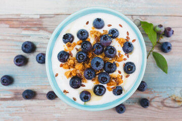 Yogurt with granola and  fresh blueberries on the wooden table
