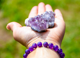 Natural mineral amethyst in hand. Semi-precious multi-colored stones, minerals close-up....