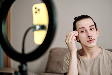 Young gay man recording makeup tutorial video