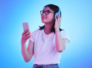 Woman, student and phone with headphones listening to music, techno streaming and radio on blue...