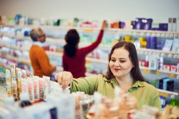 A pretty looking for a cream for skin care while man and women shopping behind.