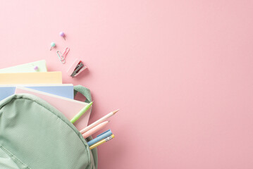 Schoolgirl's delight: Top view of open sage backpack with pencils, pens, notebooks, mini stapler,...