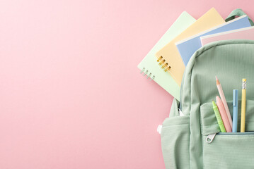 Chic girly learning essentials setup. Top view of open sage backpack with stationery, pencils,...