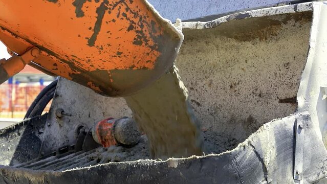 Truck Mixer Pouring Concrete into Concrete Pump. Concrete Pouring During Commercial Concreting Floors of Buildings at the Construction site.