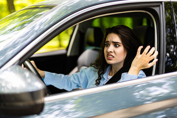 Angry female driver driving a car. Angry young woman stuck in a traffic jam.