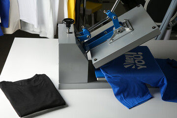 Printing logo. Heat press with blue t-shirt on white table