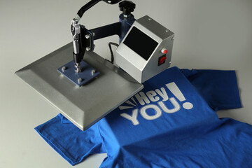 Printing logo. Heat press with blue t-shirt on white table